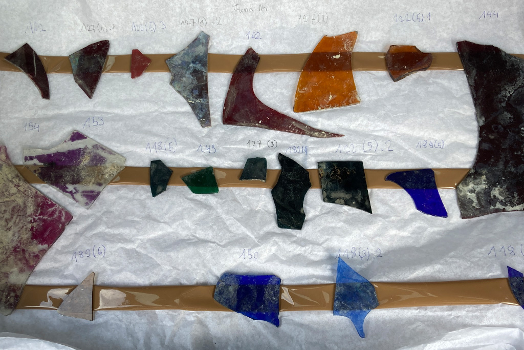 Verschiedenfarbige aufgereihte Bruchstücke von Glasscherben 