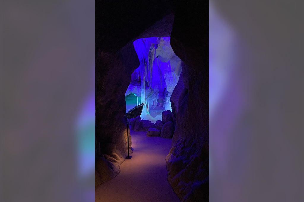 Dunkler Gang mit blau leuchtender Grotte in der Bildmitte